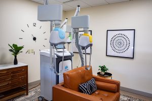 TMS therapy treatment room with two mounted head coils above an orange leather couch