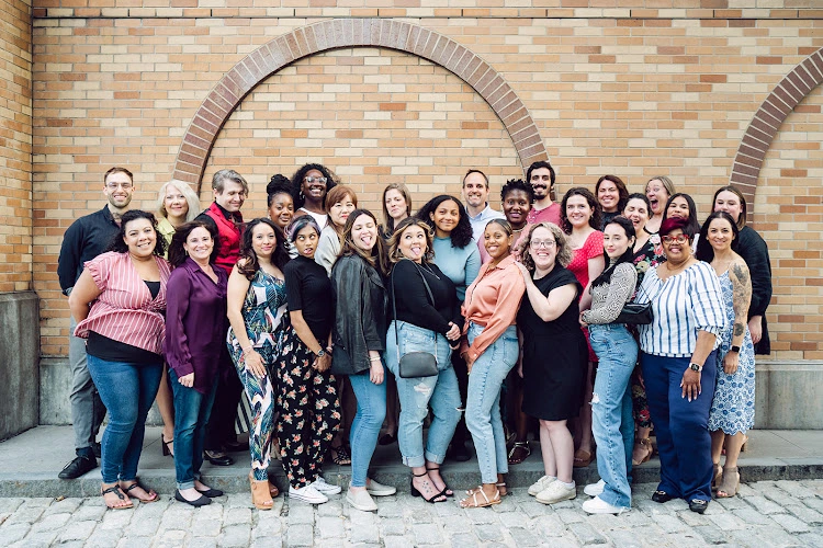 Resolution Counseling Center team of 30+ diverse staff members posed together in front of brick archway