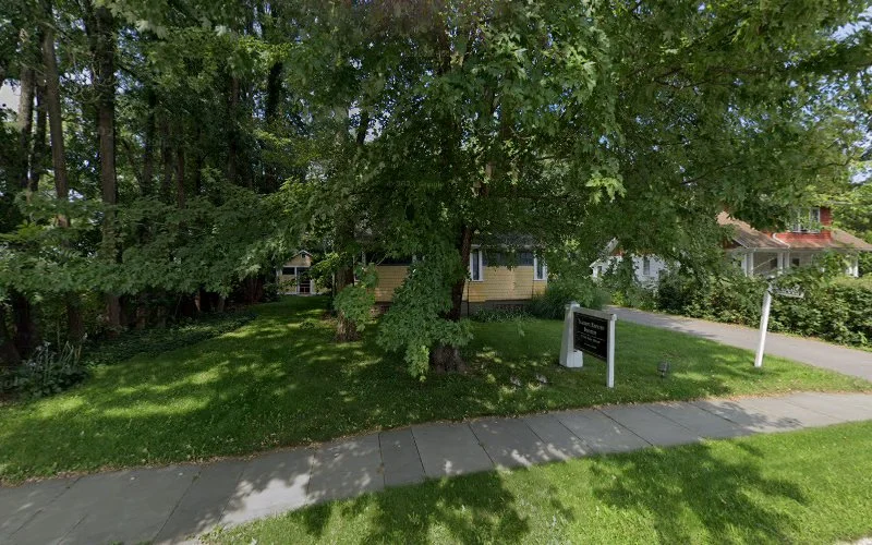 Rising Lotus Counseling building exterior with yellow siding surrounded by mature trees and green lawn