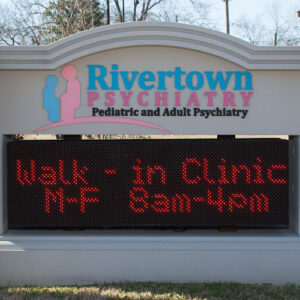 Rivertown Health pediatric and adult psychiatry clinic exterior sign reading 'Walk-in clinic M-F 9am-4pm'