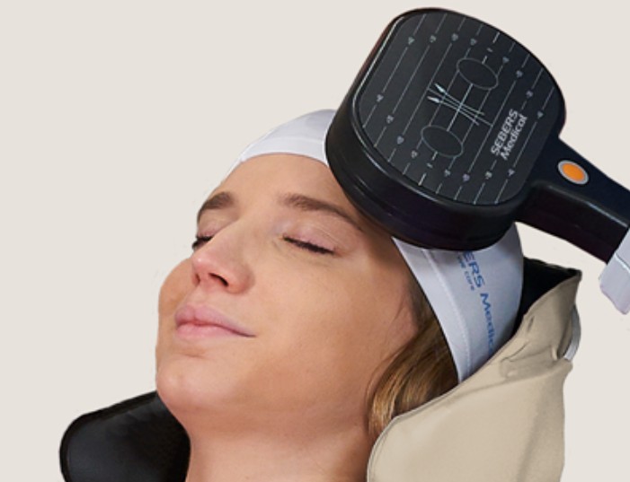 Clinician applying TMS device to patient's head during transcranial magnetic stimulation treatment