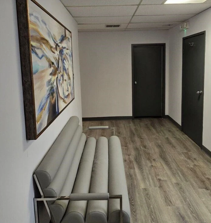 Clinical waiting room with beige rolled cushions, artwork, and two black doors