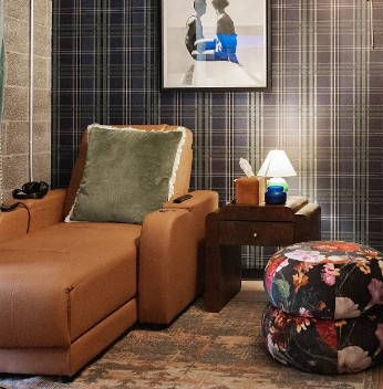 Cognac leather sofa with green pillow, side table, and patterned ottoman in waiting room
