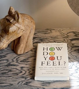 Wooden cat sculpture and 'How Do You Feel?' card on patterned surface