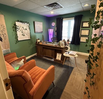 TMS therapy clinic reception area with green walls, orange chairs, wooden desk, and purple accent lighting