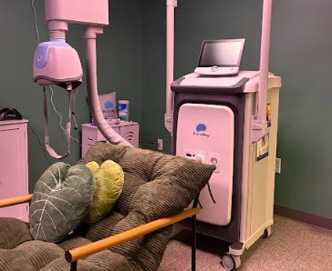 Pink transcranial magnetic stimulation device next to treatment coil on yellow and gray cushion