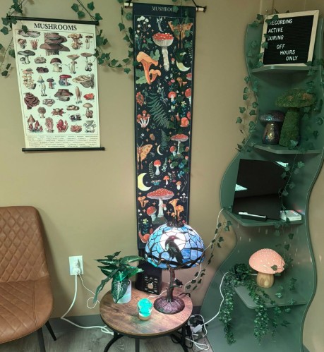 Clinic corner with mushroom and forest-themed wall art, globe, wooden side table with plants and decor