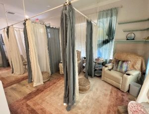 Private therapy room with hanging curtain dividers, cream seating areas, and warm wood flooring