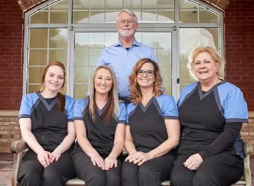 TMS therapy clinic staff team of five posing outside brick building entrance
