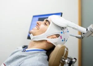 Patient receiving TMS therapy with coil applicator positioned on scalp during clinical session