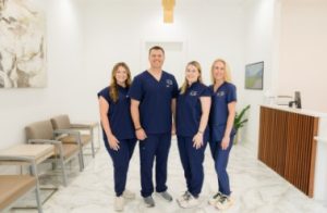 Four staff members in navy scrubs standing in modern clinical waiting area