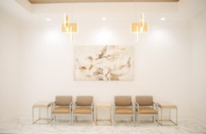 Modern waiting room with four cushioned chairs and abstract artwork on wall