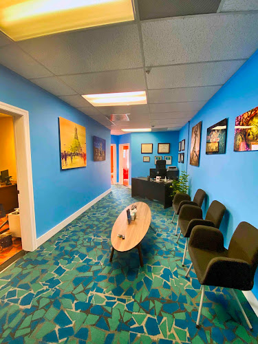 Office waiting room with bright blue walls, colorful artwork, reception desk, and seating area