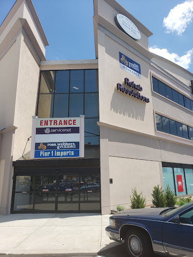 Modern clinic building exterior with entrance sign and parked car in front