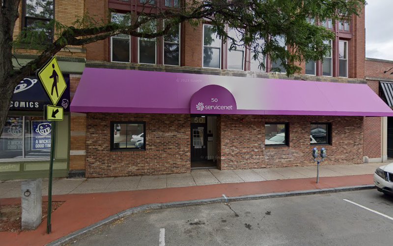 Servicenet storefront with purple awning and brick facade on street level