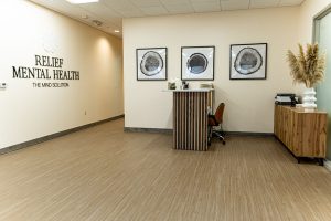 Relief Mental Health clinic reception area with wall signage, three framed brain illustrations, and wooden furniture
