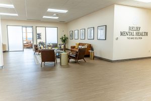 Relief Mental Health waiting room with brown leather chairs, side tables, framed artwork, and glass doors to adjoining spaces
