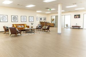 Relief Mental Health large open treatment space with brown leather seating arrangement, geometric wall art, support column, and glass partitions