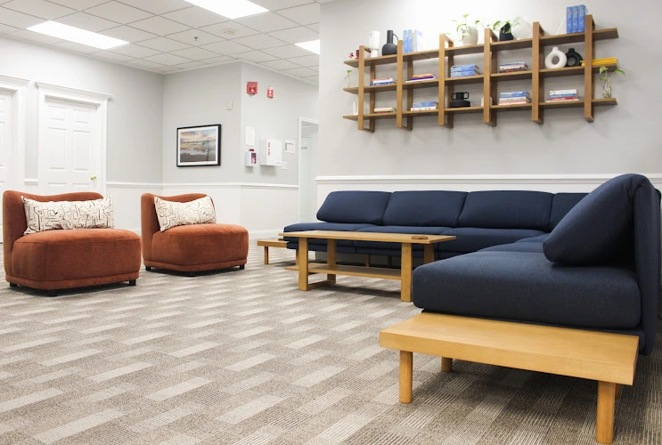 Modern recovery center waiting area with orange and navy seating, wooden shelving, and light wood accents