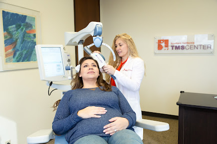 Clinician positioning TMS coil on patient's head during treatment session at Southern California TMS Center