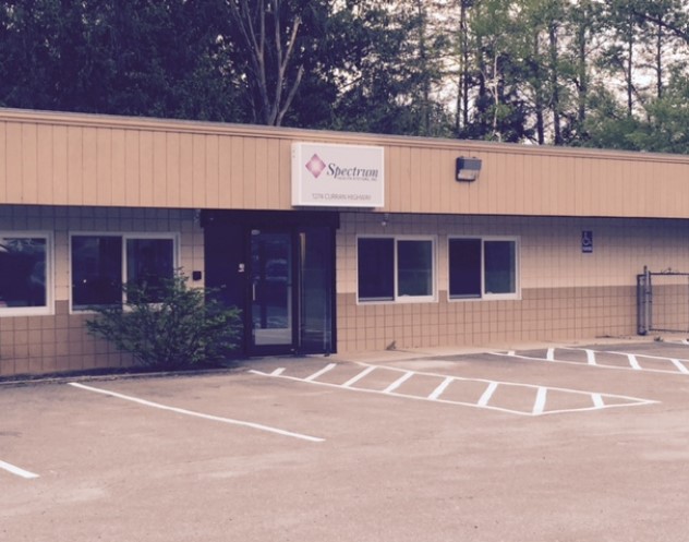 Spectrum Health Systems building exterior with tan siding, entrance doors, and parking lot