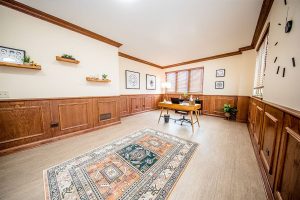 Quiet consultation space with wooden desk, chair, decorative shelving, and wall art