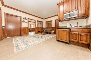 Open reception area with wooden cabinetry, kitchenette, and seating area in warm wood tones