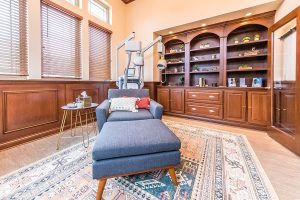 Relaxation room with blue chaise lounge, side table, TMS device, and built-in wooden shelving