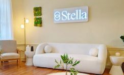 Stella clinic Boston reception area with white neon logo, modern sofa, accent chairs, and living plants