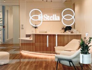 Stella neon sign above reception desk in modern clinical office with treatment chair and plants