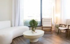 Bright contemporary therapy lounge with curved white sofa, mid-century wood chairs, and natural lighting