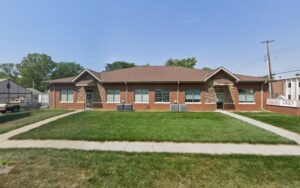 Single-story red brick medical clinic building with front lawn and clear signage