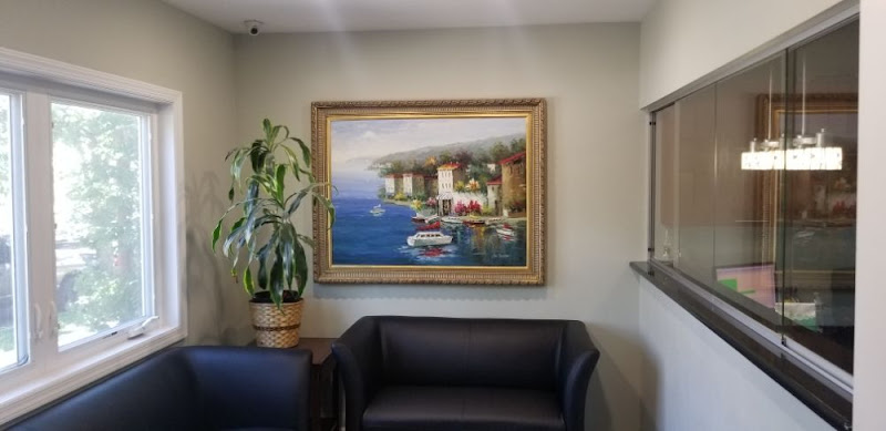 Therapy office waiting room with black sofa, framed landscape painting, potted plant, and window view