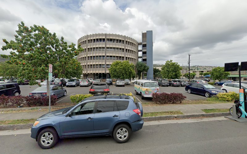 Parking lot with blue SUV in foreground and circular brutalist building in background