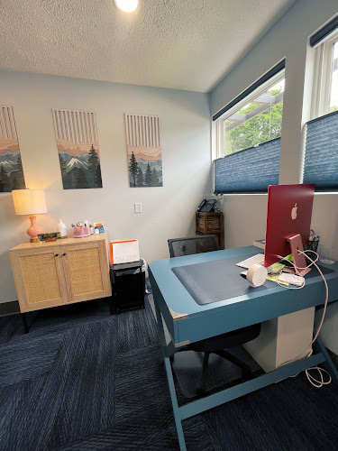 Clinic office with blue desk, computer monitor, wooden storage cabinet, and landscape artwork