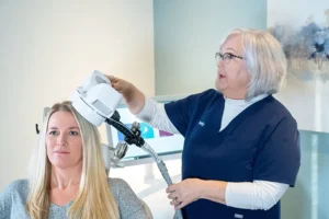 Clinician administering TMS treatment to patient using handheld magnetic coil device