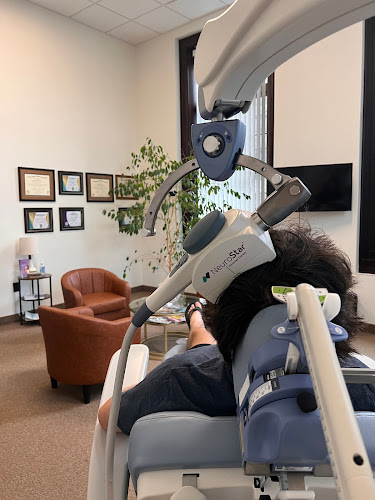 Patient receiving transcranial magnetic stimulation treatment with coil positioned on head in clinical office