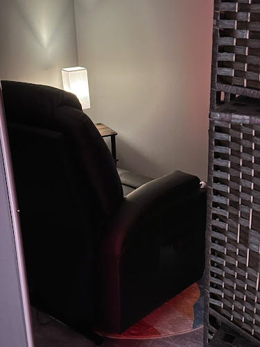 Patient sitting in black chair in dimly lit therapy room with mood lighting