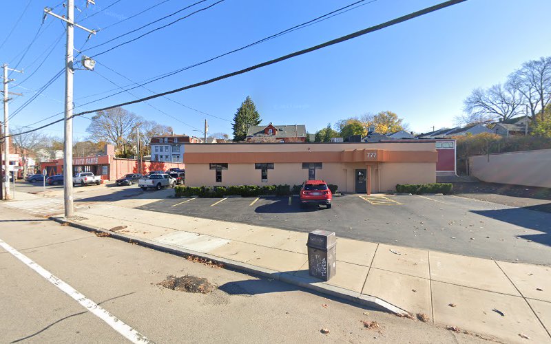 Single-story tan medical office building with parking lot and parked cars on residential street