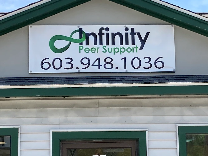Infinity Peer Support sign with green logo and phone number 603.948.1036 on building exterior