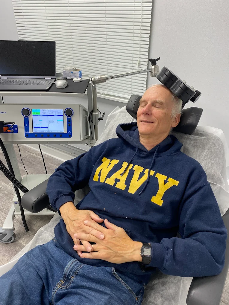 TMS of Emerald Coast advertisement showing man with head in hand, text reads FDA approved treatment of depression and other mood disorders, veteran backed and endorsed clinic