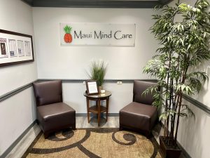 Maui Mind Care waiting area with brown leather chairs, bamboo plant, small table, and pineapple-brain logo sign