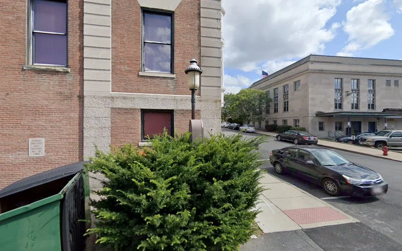 Brick behavioral health services building with purple windows, street view with parked cars and adjacent institutional building