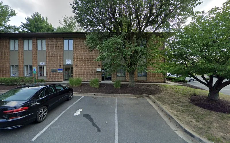Brick behavioral health clinic building with large tree and parked car in front