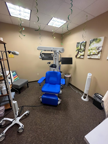 TMS therapy treatment room with blue patient chair beneath mounted magnetic coil device