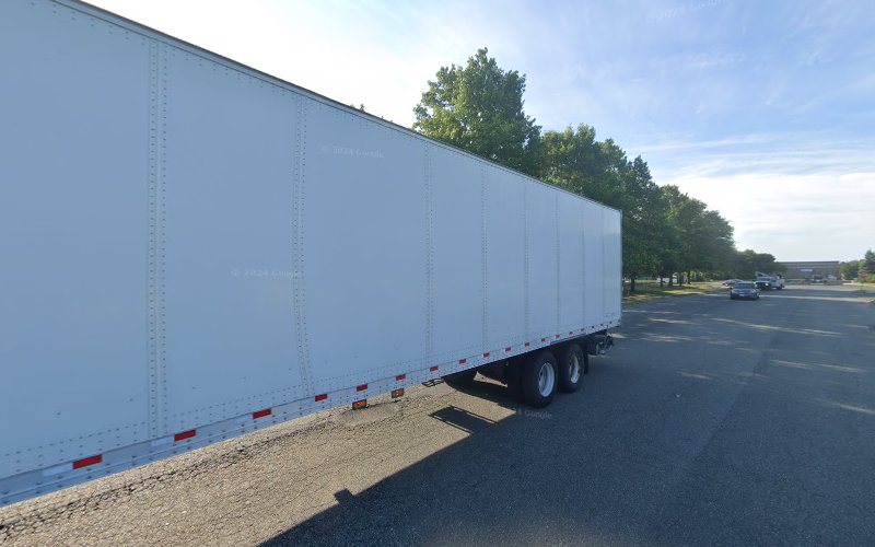 White semi-truck parked in lot with trees and buildings in background