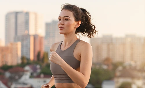 Woman in athletic wear looking energized with city skyline in background