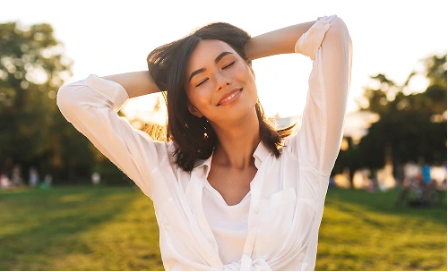 Woman in white shirt relaxing outdoors in golden sunlight