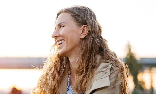 Woman smiling outdoors near water, representing wellness from Vital Restore IV therapy