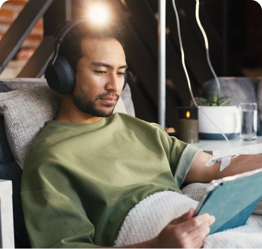 Man wearing headphones and green shirt reading a tablet while sitting on a couch